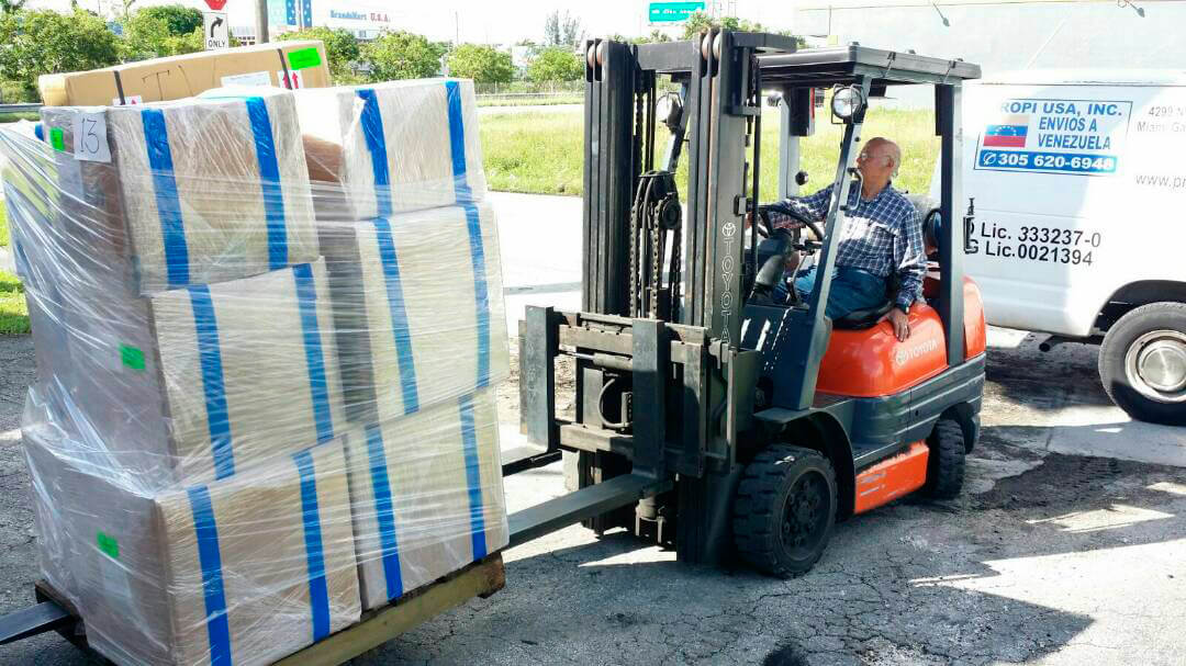 Forklift loading a shrink-wrapped pallet next to a PROPI USA delivery van